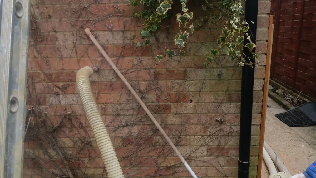 Cavity wall insulation being injected through the mortar joints of a brick wall