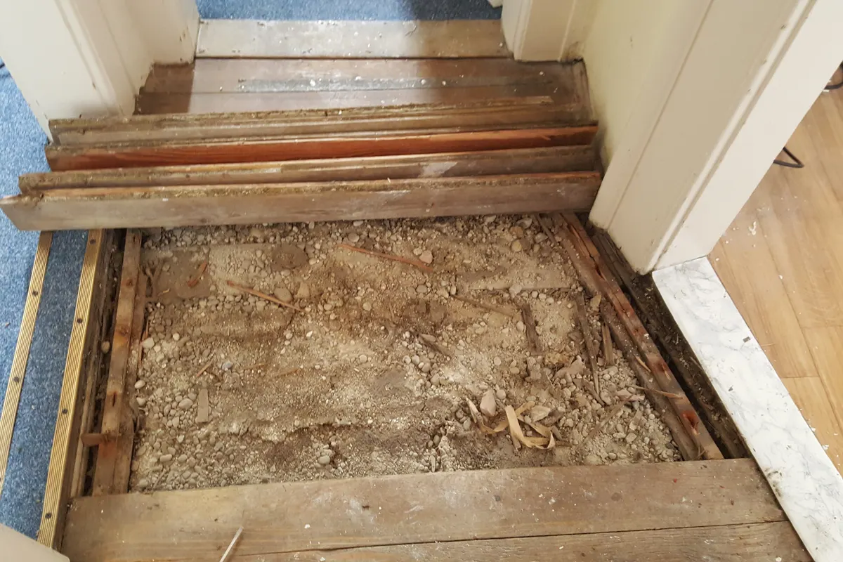 Mineral wool insulation held between floor joists under lifted timber floorboards